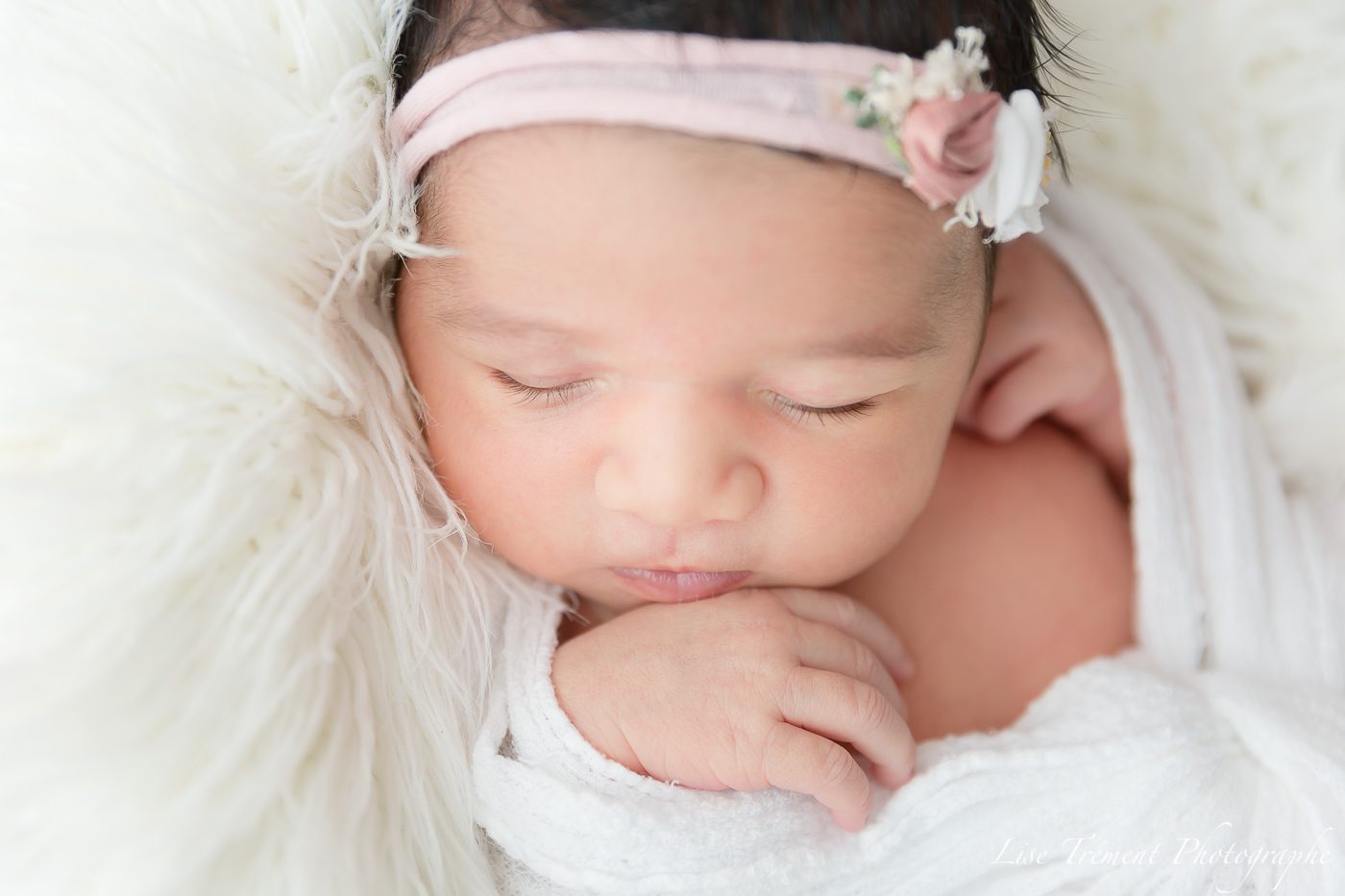 Bébé endormi, bien emmaillotée dans un wrap blanc avec un joli bandeau fleuri rose bébé, séance photo, photo de bébé, studio, Lise Trement photographe, Soisy sous montmorency, Enghien, val d'Oise